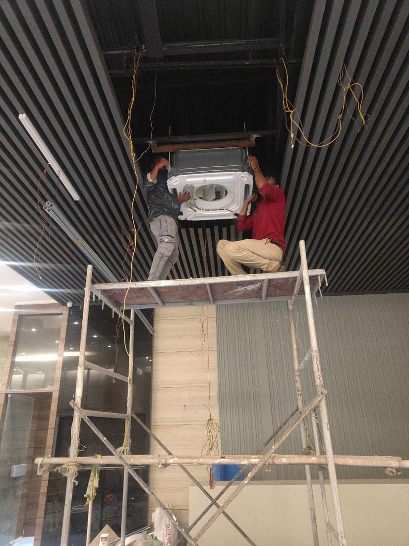 Universal Services technicians installing a ceiling cassette AC unit