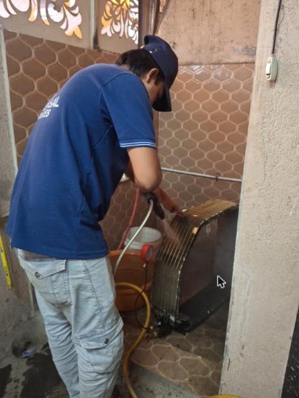 Universal Services technician jet-cleaning an AC unit