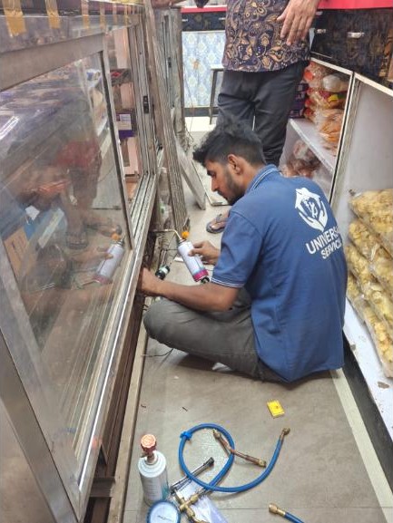 Universal Services technician repairing a commercial display freezer