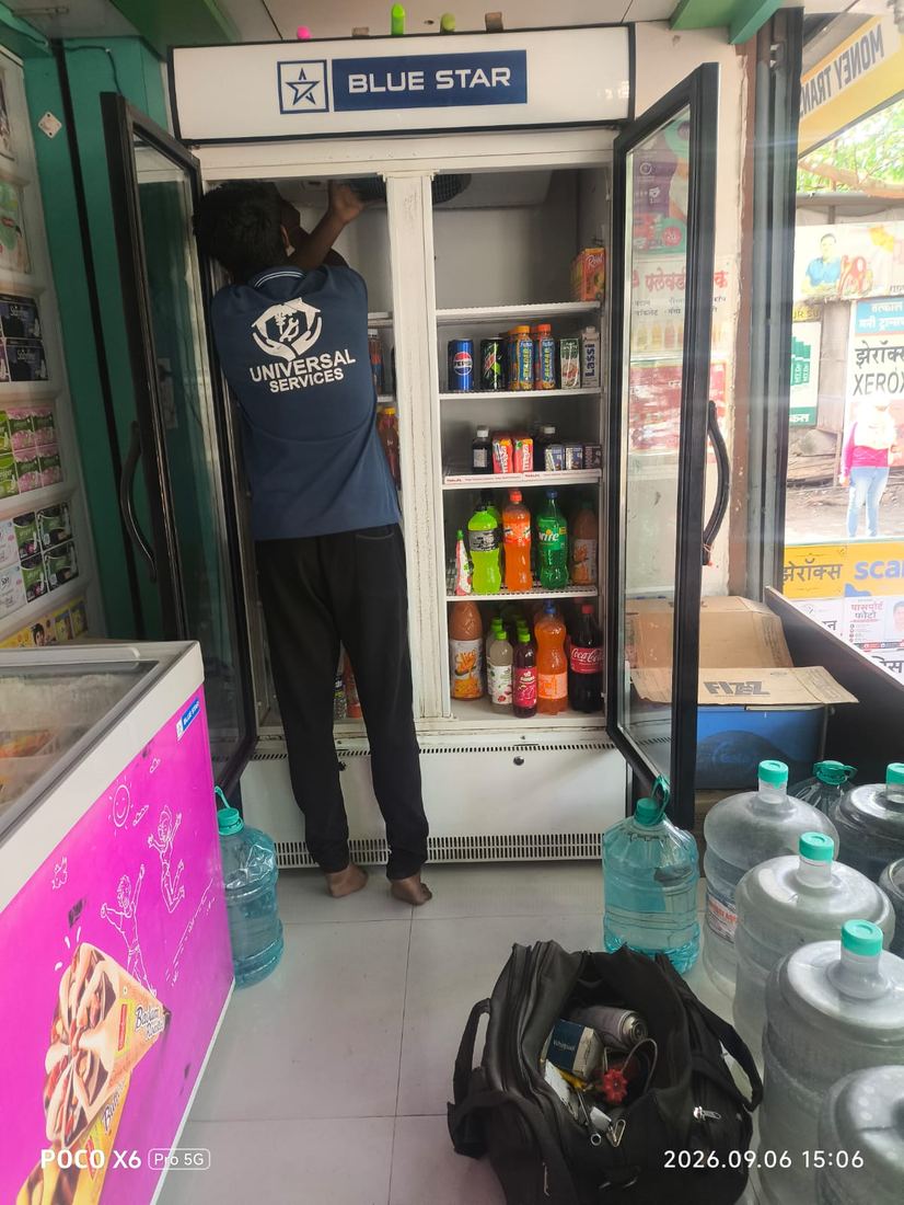 Universal Services technician repairing a commercial visi-cooler unit at a shop