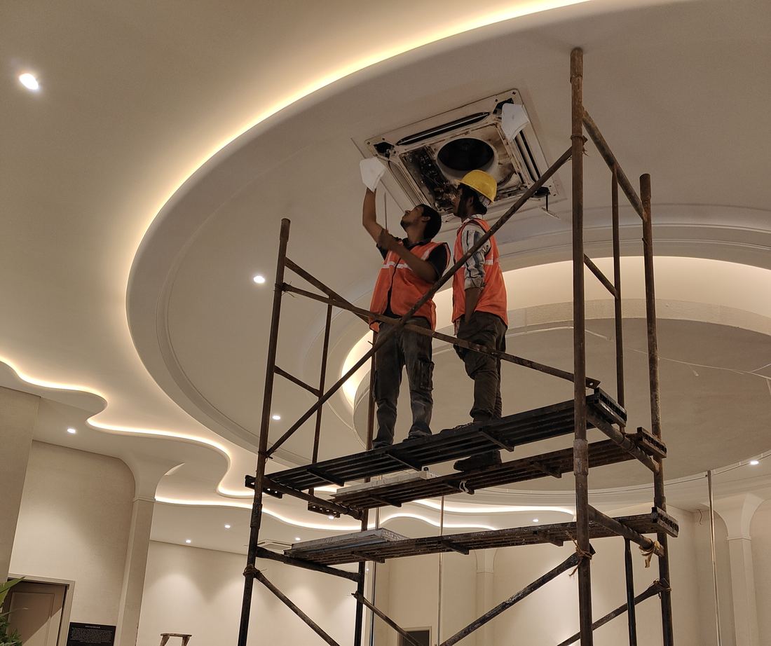 Universal Services technicians servicing a ceiling-mounted cassette AC unit