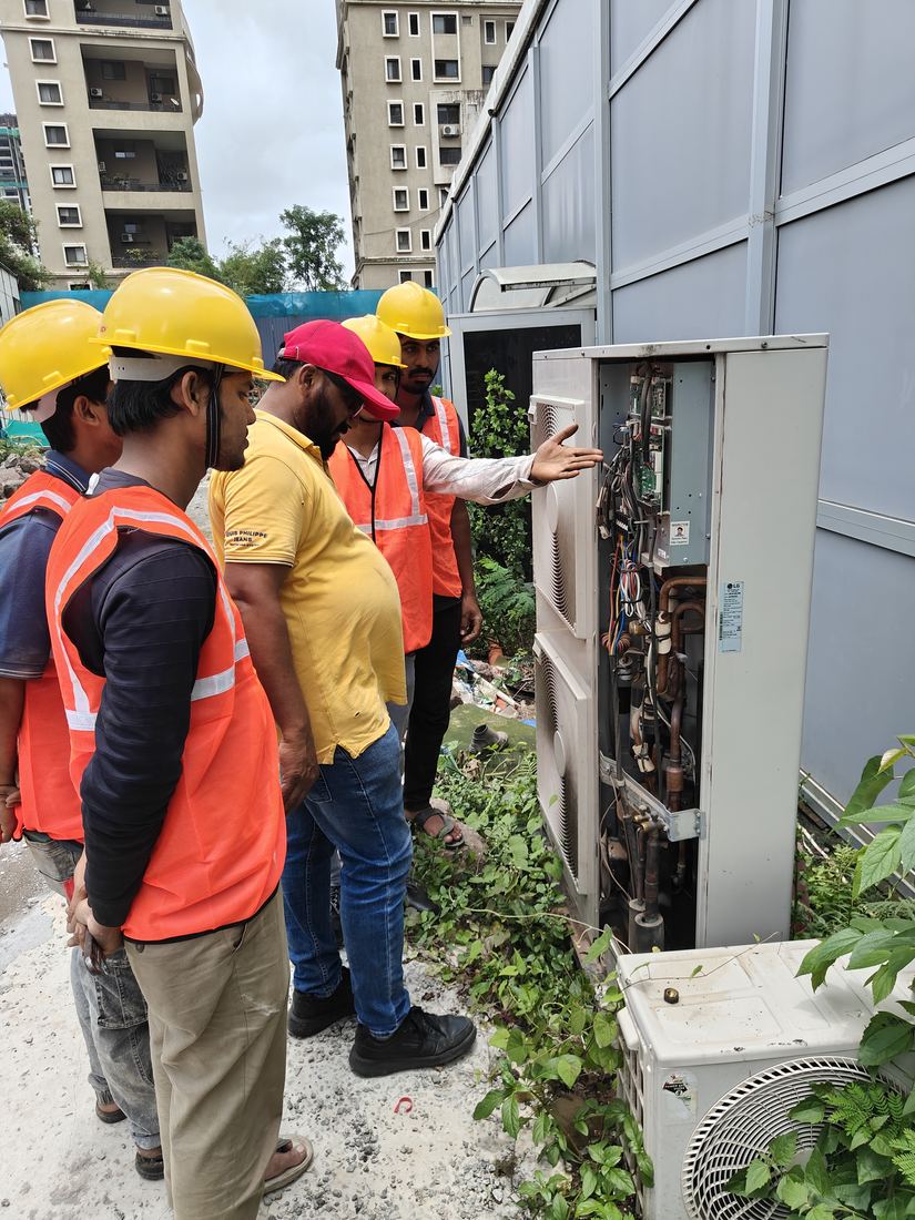 Universal Services team inspecting an outdoor VRF AC unit at a housing complex